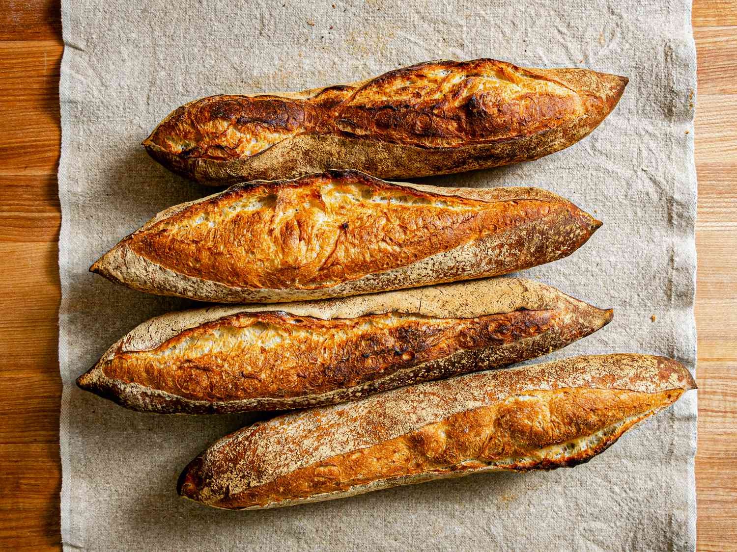 Four rustic French baguettes on natural linen