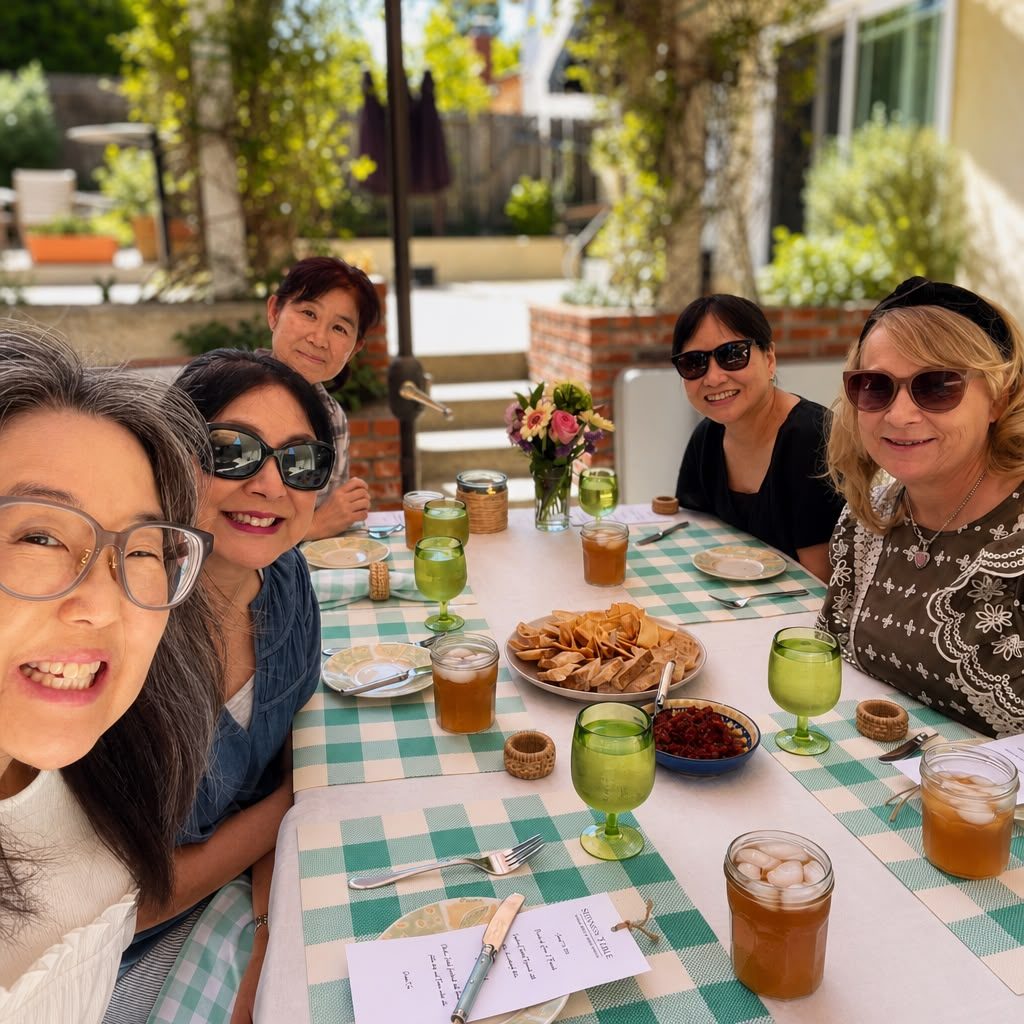 Guests seated at the gingham lunch table with iced tea and a platter of pita, smiling at the camera — Patio Lunch at Sienne's Table