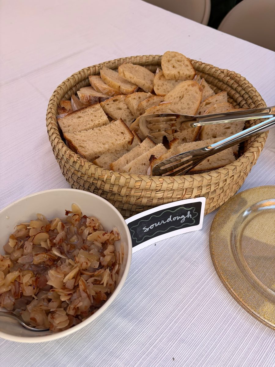 Basket of sliced sourdough with a chalkboard sign and a bowl of caramelised onion and almond spread — Sienne's Table Open House