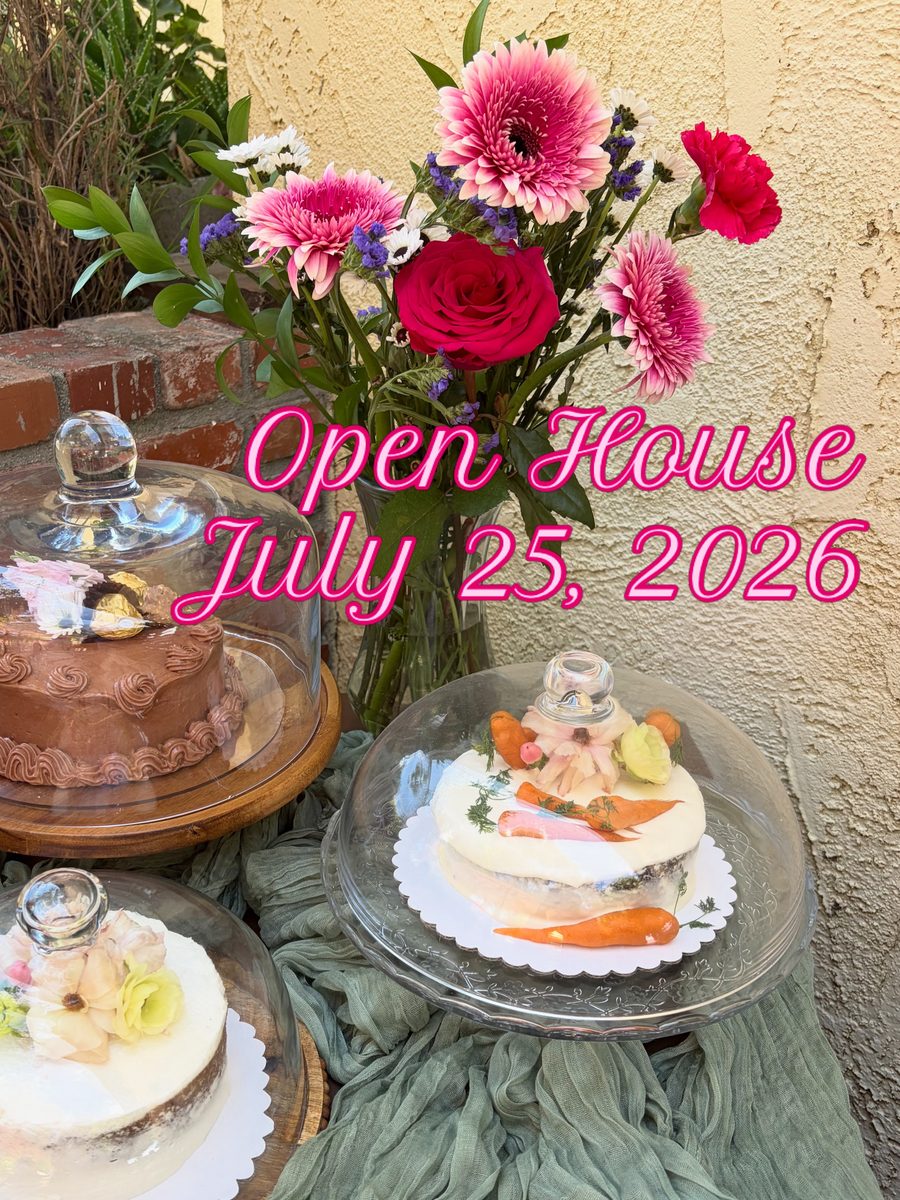 Three cakes under glass domes on a brick patio with a vase of pink gerberas — the dessert table at the Sienne's Table Open House, Lomita CA