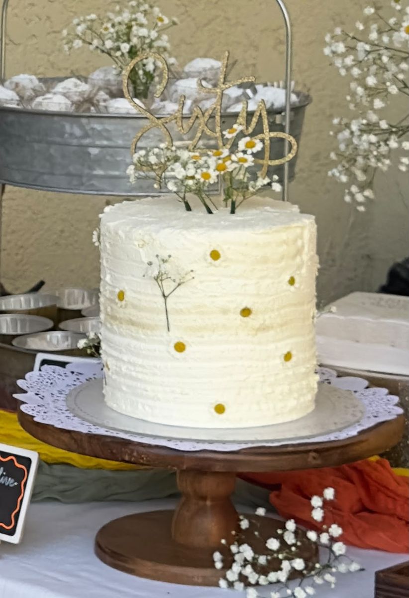 Tall textured buttercream cake with daisy dots, baby's breath, and a gold Sixty topper — custom 60th birthday cake by Sienne's Table