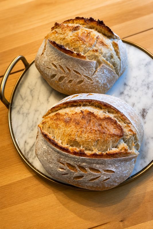 Two artisan sourdough boules on a marble board — freshly baked in small batches at Sienne's Table, Lomita CA