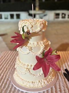 A three-tier buttercream cake with red lilies