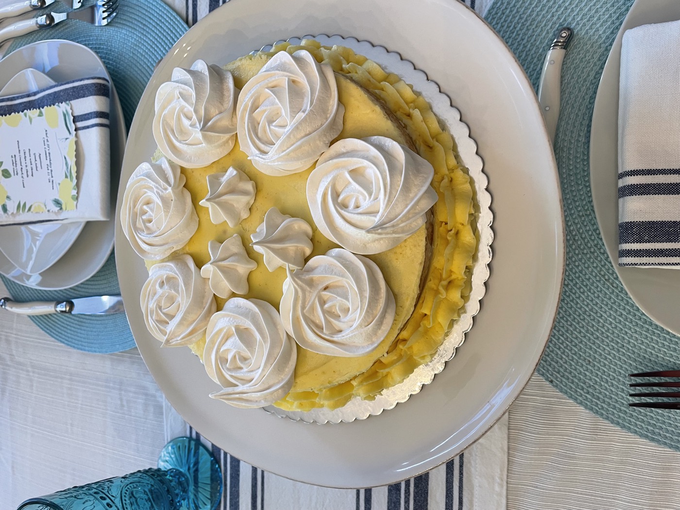 A lemon meringue cake on a place setting with blue linens